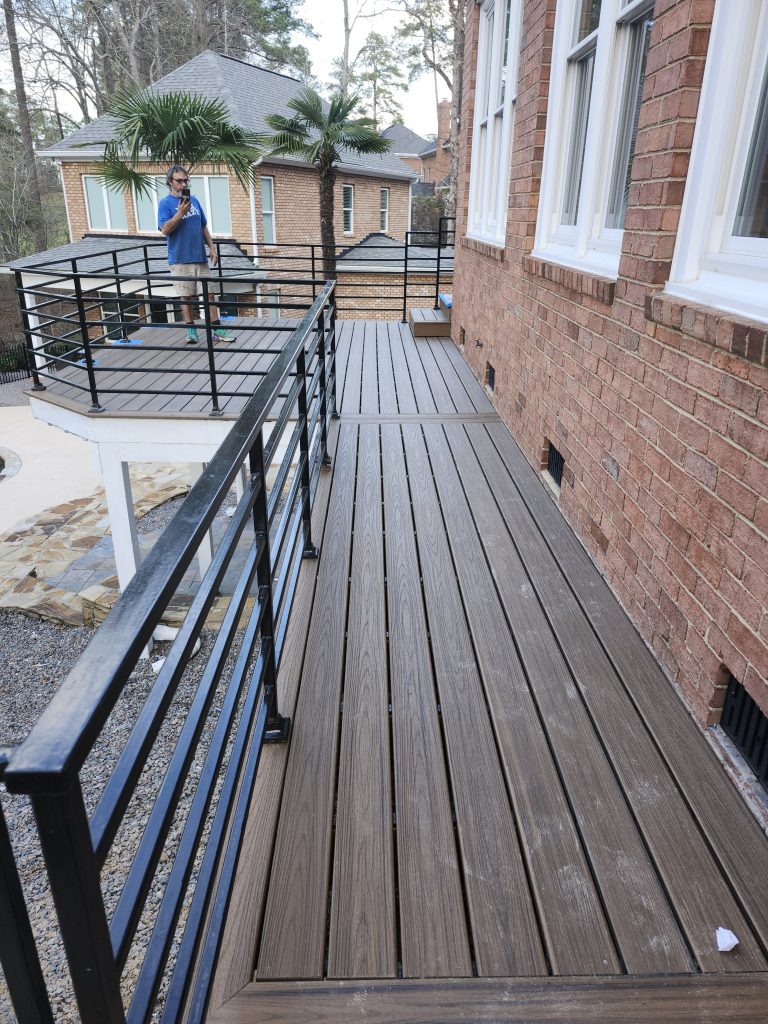 Professional installation of modern composite siding panels on brick residential exterior with metal stair railings during active construction renovation project.
