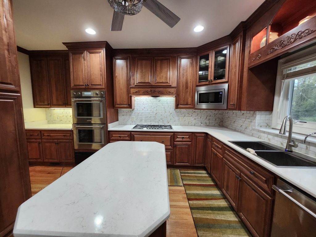 Luxury kitchen with dark wood cabinetry, marble countertops, subway tile backsplash, and stainless steel appliances.