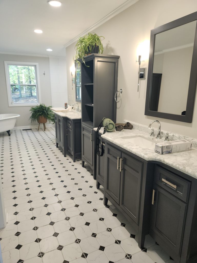 Modern bathroom renovation featuring geometric black and white tile installation, custom black cabinetry, and recessed lighting.
