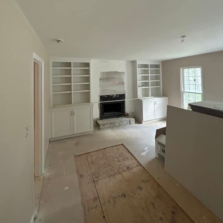 Custom built-in cabinetry and fireplace installation during mid-stage interior renovation with professional framing and finishing work.