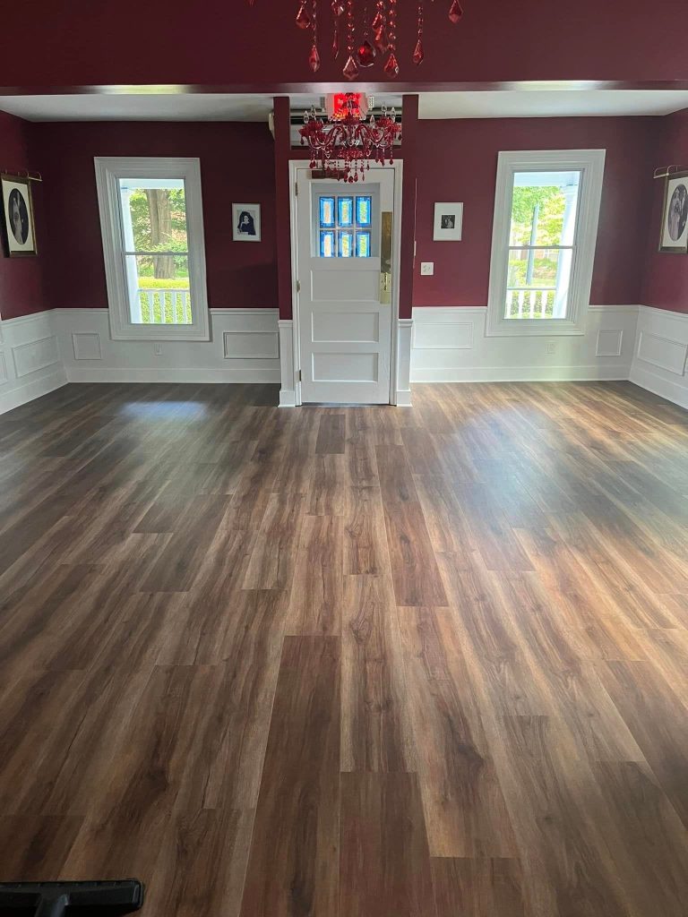 Elegantly finished interior room with burgundy walls, white wainscoting, and professionally installed laminate wood flooring in rich brown tones.