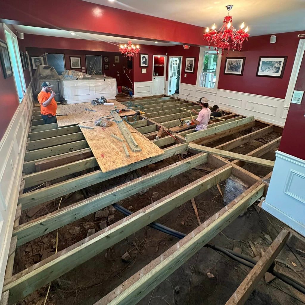 Professional contractors installing subfloor framing and structural repairs in upscale restaurant interior renovation project in Aiken, SC.