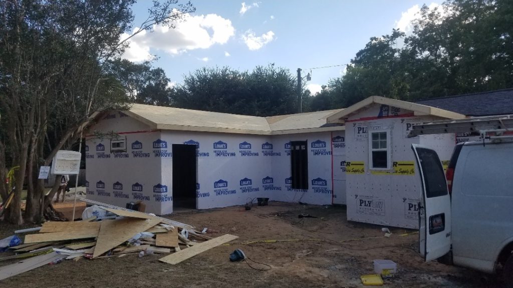 Professional residential construction project in Aiken SC showing home addition framing with protective house wrap and staged building materials.