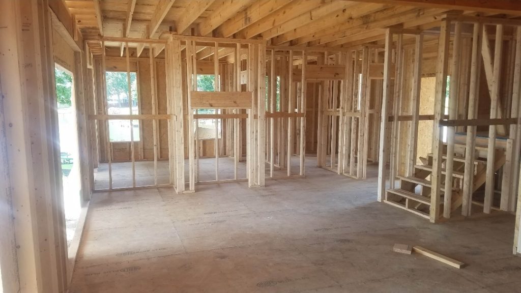 Residential framing stage showing wooden studs, beams, and floor joists during custom home construction in Aiken, SC.
