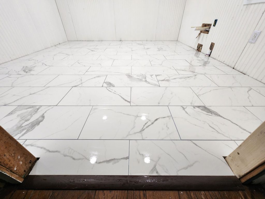 Professional tile installation of marble-look porcelain in herringbone pattern during bathroom remodeling project in Aiken.